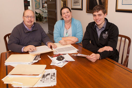 Three people at a kitchen table looking at photos